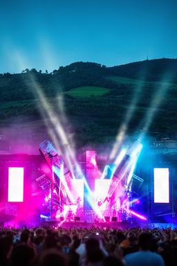 Escenario iluminado del BBK Live con las colinas de Bilbao al fondo