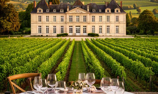 Château de Burdeos rodeado de viñedos verdes y mesa preparada para una cena