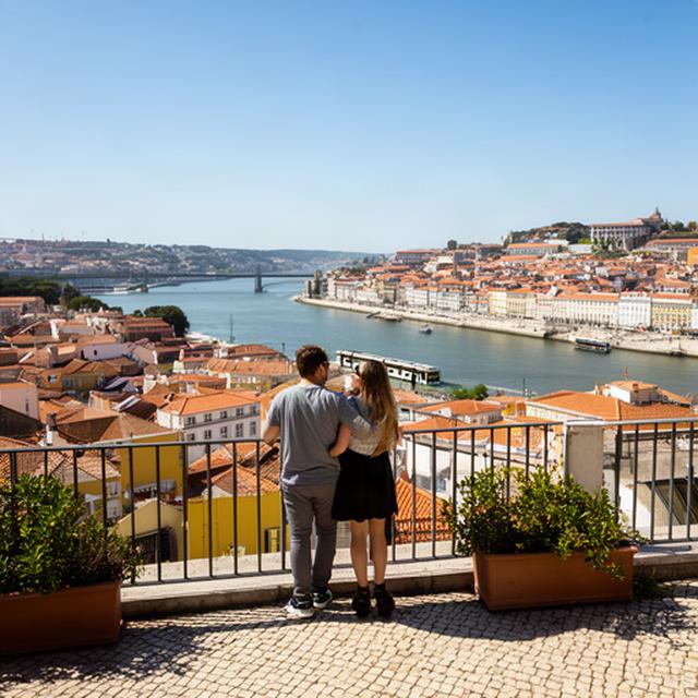Pareja mirando el río Tajo desde un mirador soleado de Lisboa