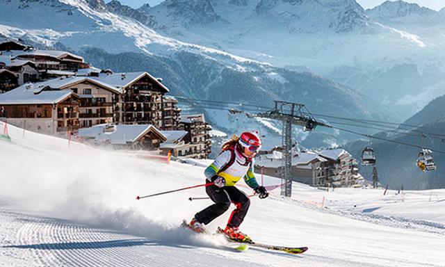 Esquiadora en una estación de los Alpes franceses con pistas y alojamiento de montaña