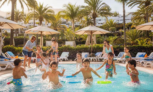 Niños jugando junto a una piscina de hotel en unas vacaciones familiares en Canarias