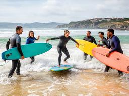 Equipo de empresa practicando surf en una playa de la costa vasca